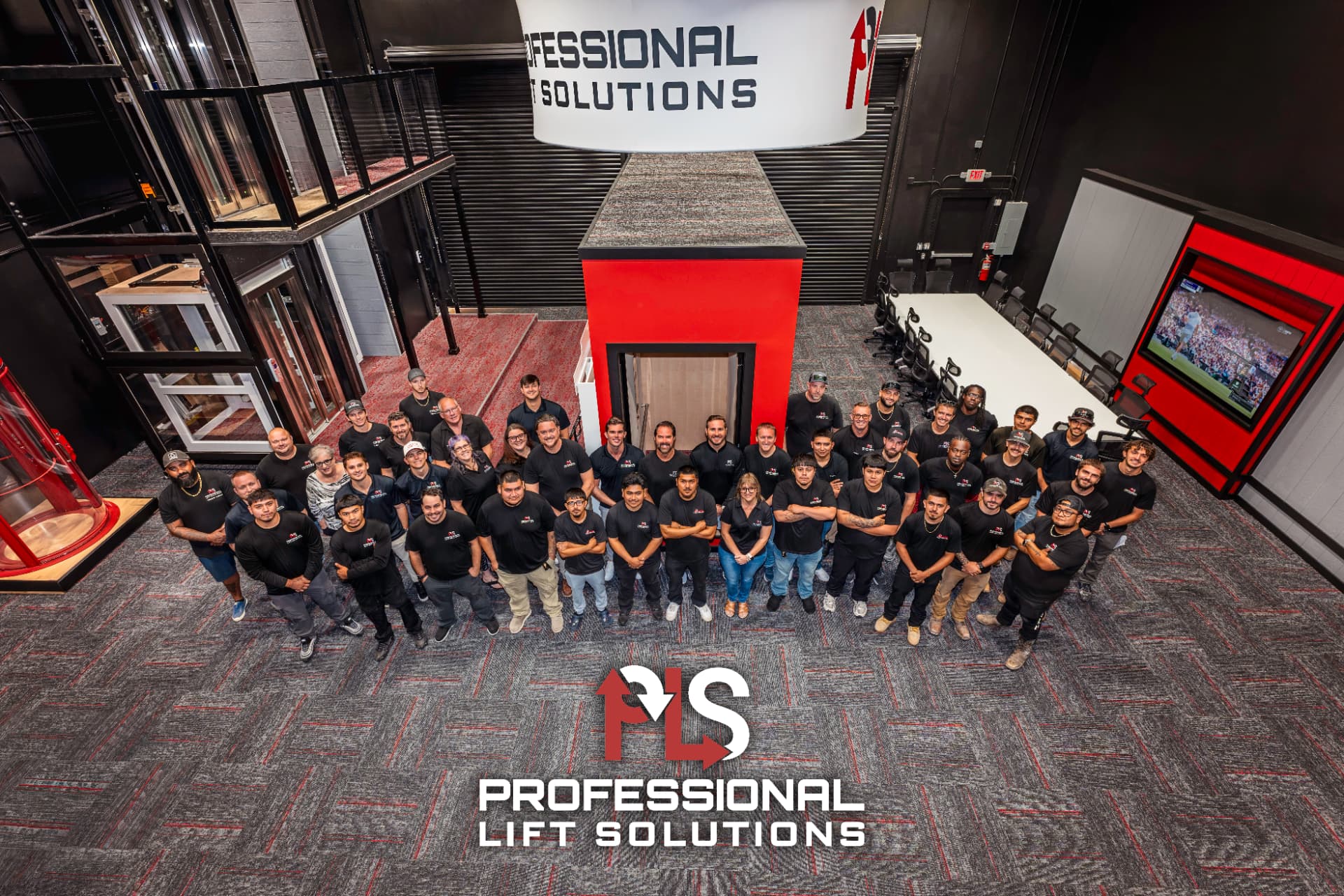The Professional Lift Solutions team gathered in the Sarasota showroom beneath the company sign