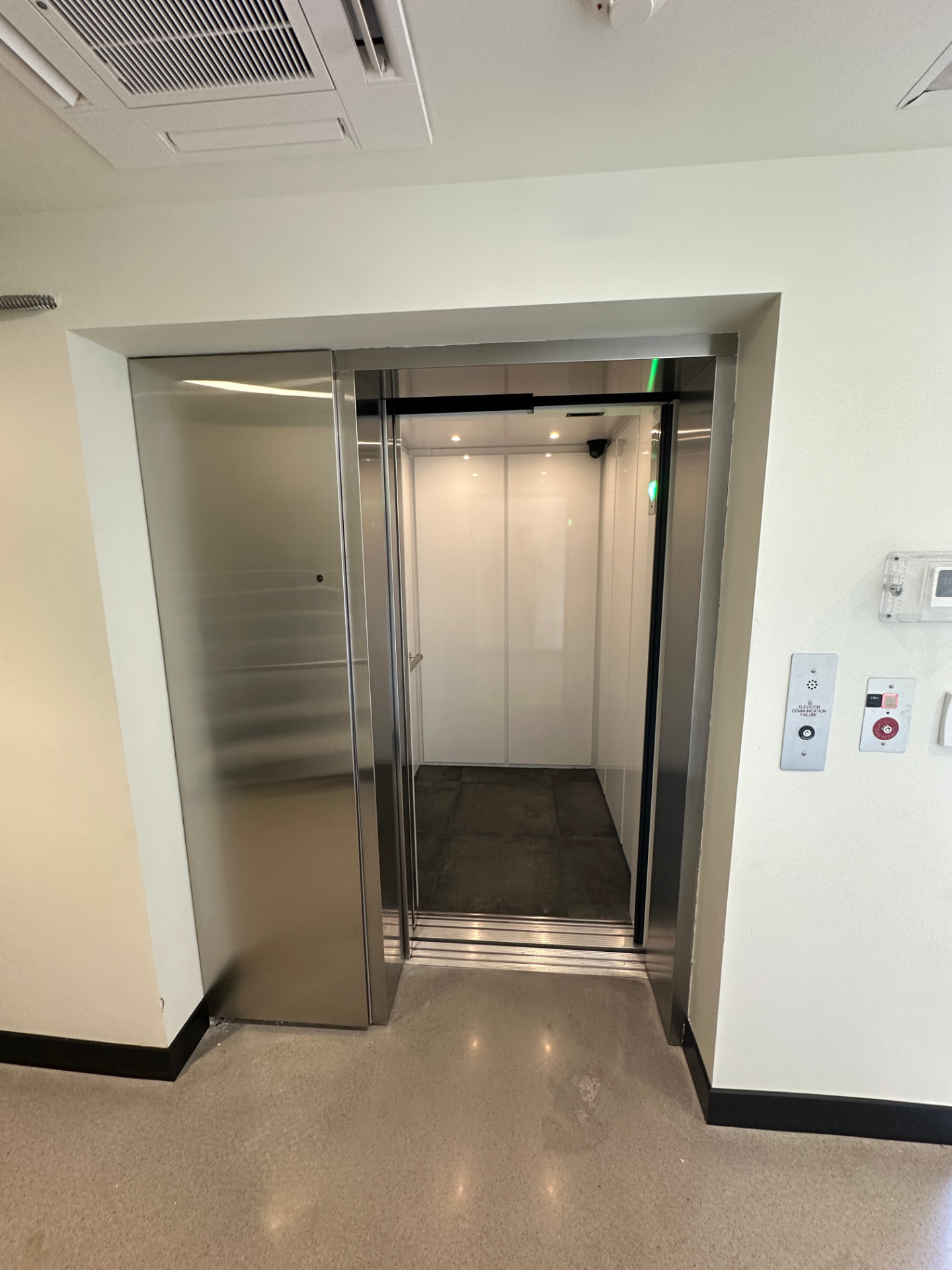 LU/LA elevator entrance with stainless steel doors and hall call station in a commercial corridor