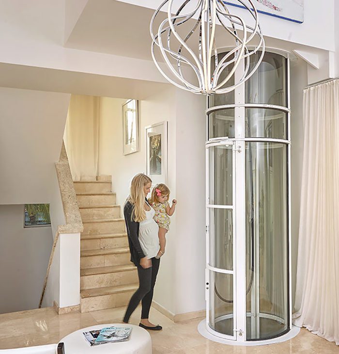 Woman holding child by home glass elevator